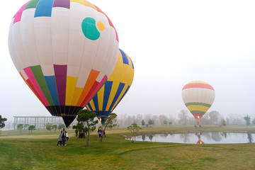 Aterrizaje de tres globos aerostáticos de varios colores en el campo cerca de un lago 