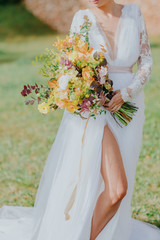 La mariée, pieds nus, tenant son bouquet de fleurs dans le vent