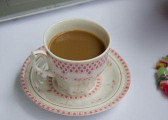 Coffee in the office, close-up of the desk with beautiful decorated cup with hot beverage, business concept