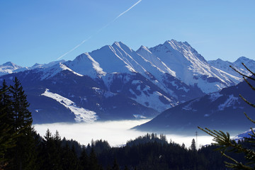 beautiful view to the snow capped mountains in austria with a misty valley