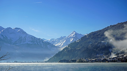 beautiful view over the zeller lake to the kitzsteinhorn in austria on a sunny winterday with clear blue sky