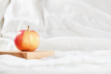 Fresh red apple a on white bed in the morning. Clode up.