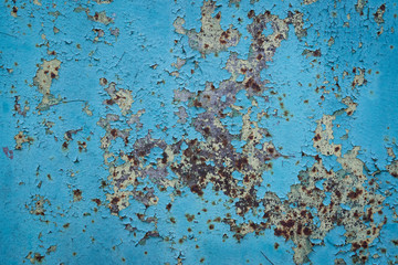 Metal fence with old blue paint. Peeled paint. Yellow, red hue with rust.