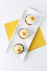 Carrot cupcakes with cream and walnut on a white plate. Vertical orientation, top view.