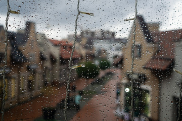 festive street garland with lanterns on glass background with raindrops. On this plan, in a blurry...