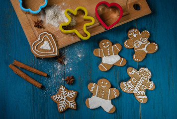 Gingerbread cookie in the shape of little men lies on a blue wooden table.