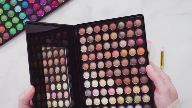 Flat lay. New eyeshadow palette with makeup brushes on marble background.