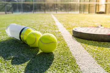 paddle tennis racket and tube with balls on court