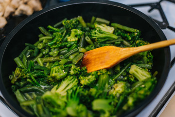 Cooking stewed vegetables, broccoli and young beans in a frying pan.