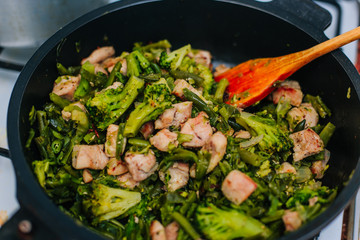 Stewed vegetables in a pan with fried chicken. Stir with a wooden spatula while cooking