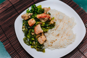 White plate with broccoli and beans stewed vegetables with chicken.