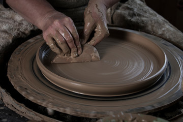 Hand craft making pottery on wheel. Female hands mold ceramic plate from clay