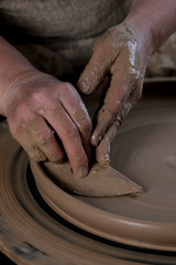 Hand craft making pottery on wheel. Female hands mold ceramic plate from clay