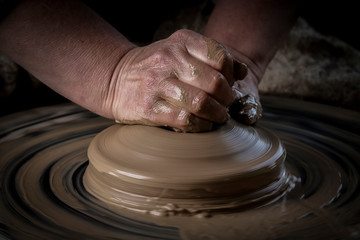 Hand craft making pottery on wheel. Female hands mold ceramic plate from clay
