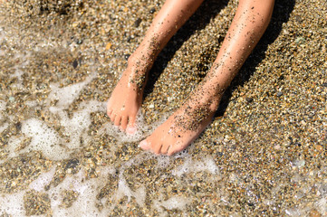 children's feet in the sea sand and water