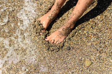 children's feet in the sea sand and water