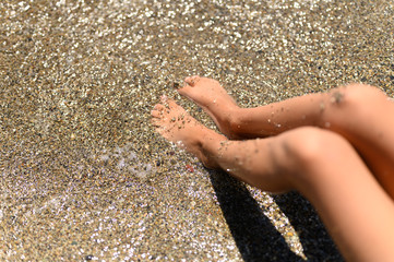 children's feet in the sea sand and water
