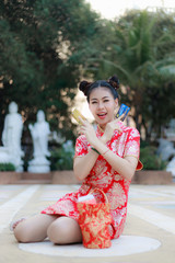 Naklejka premium Portrait of beautiful Asian woman wearing red cheongsam and showed credit cards with red cloth bag. Chinese New Year, which is the culture of the Chinese nation, will have shopping and gifts.