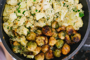 Potatoes with greens in a pan and fried Brussels sprouts. Stewed potatoes with dill.
