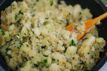 Potatoes with greens in a pan. Stewed potatoes with dill.