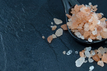 Pink Himalayan salt on a black rock ground.