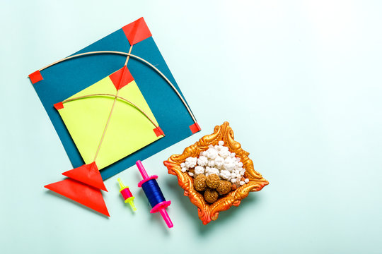 Celebrate Indian festival makar sankranti with colorfull kite,sesame seed ball,tilgul and chakri with background