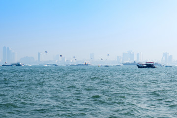 a lot of Boat are Floating on Blue sea , a lot of glider in sky And so Far building