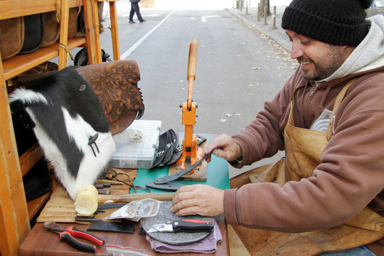 Working process of leather craftsman. Tanner or skinner sews leather or fur on a special machine