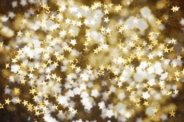 Weihnachtlicher Hintergrund mit goldenen Sternen auf dunklem Untergrund.
