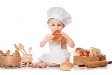 Little baby boy baker enjoying making and eating food. Little baker