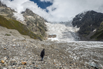 Tourist looking at huge glacier Adishi in mountains of Svaneti Georgia while trekking