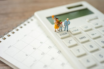 Family Miniature people Pay queue Annual income (TAX) for the year on calculator. using as background business concept and finance concept with copy space  for your text or design.