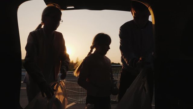 Family puts shopping bags from supermarket in car boot