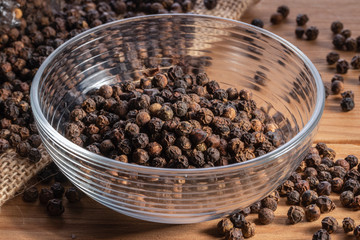 Black pepper grains in a transparent deep dish.