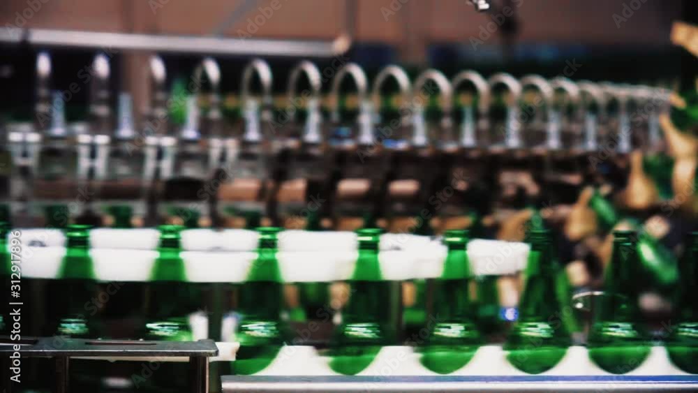 Poster panning shot inside a beer bottling line factory with automated production and processing of beer bo