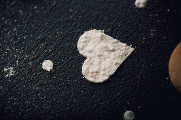 Composition with decorated heart shaped cookies on dark,black background.