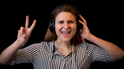 coole junge Frau mit Kopfhörern singt mit und zeigt das Peace Zeichen