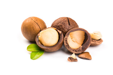Macadamia nut with pieces and green leaves isolated on a white background
