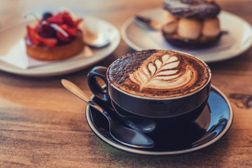 A cup of coffee with art on a table, blurred deserts on the background, toned