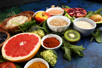 Healthy food clean eating selection: fruit, vegetable, seeds, superfood, cereals, leaf vegetable on rustic background