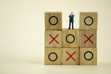 Businessman miniature standing and thinking on o x board games. (Tic Tac Toe).