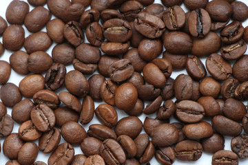 Brown roasted coffee beans on white background. Blend of 70% arabica and 30% robusta is used for this photo. Theme of drinks ingredients. Coffee background.