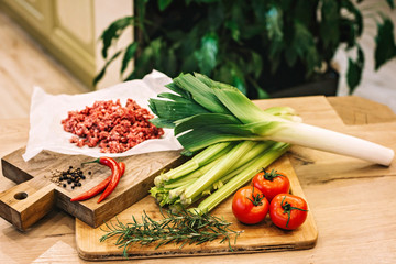 Assorted seasoning products greens and vegetables for cooking quiche lorraine pie on wooden boards.