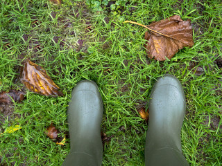 Wellington boots on the wet green grass with copy space