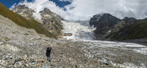 Panorama landscape with man tourist in black raincoat at glacier Lardaad