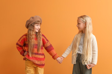 Cute little girls in autumn clothes on color background