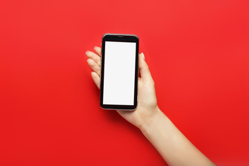 Female hand with modern mobile phone on color background