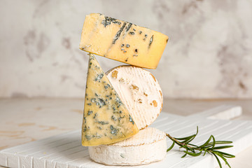 Board with assortment of fresh cheeses on grey background