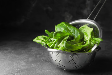 Colander with fresh spinach on table