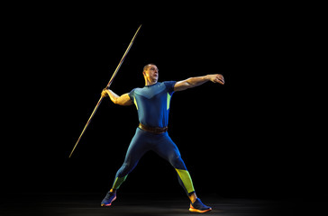 Male athlete practices in throwing javelin on black background in neon light. Professional...